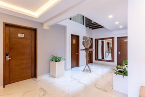 Un hall de hotel con suelo de mármol, puertas de madera y una escultura de un pájaro de colores.
