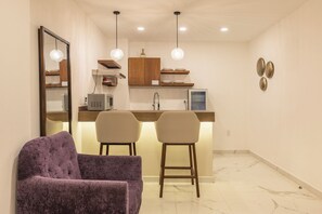 A modern kitchen with pendant lights, a built-in microwave, and a bar area with two stools. - Marvic Hotel (Playa del Carmen)