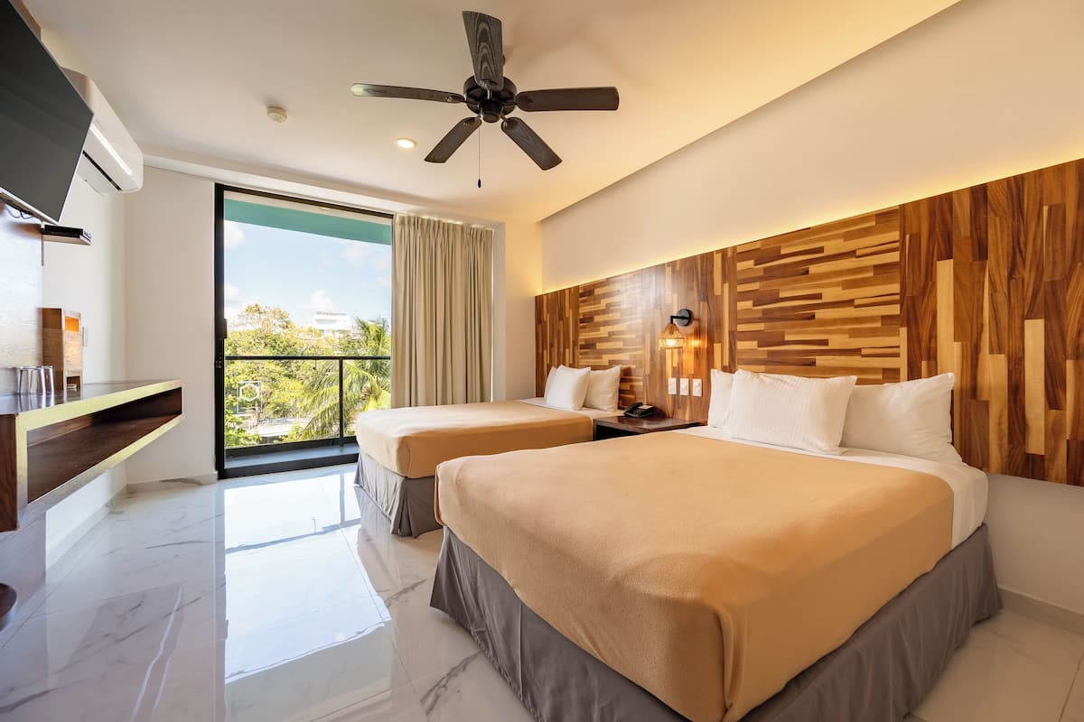 Une chambre d’hôtel avec deux lits, un ventilateur de plafond, une télévision, un balcon avec vue et un panneau mural en bois.