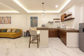A modern kitchen with a central island, a dining area with a sofa and chairs, and a living room with a couch. - Marvic Hotel (Playa del Carmen)