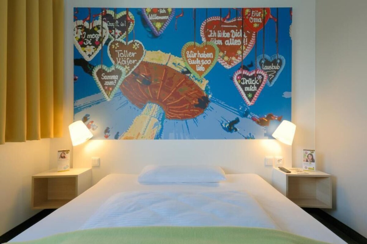Una habitación de hotel con una cama, dos mesitas de noche y un mural de pared colorido.