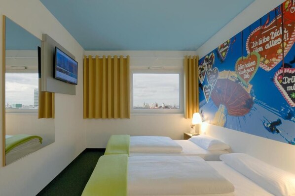 Une chambre d’hôtel avec deux lits, une télévision, une fenêtre avec des rideaux et un mur orné d’une carte colorée.