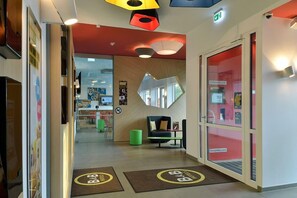 Un vestíbulo de hotel con mostrador de recepción, una zona de estar y un espejo grande en la pared.