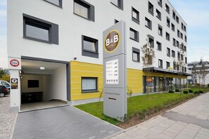 A B&B hotel with a modern design, a parking sign indicating a 1.9m height limit, and a sign pointing to the parking area. - B&B Hotel München City-west (Munich)