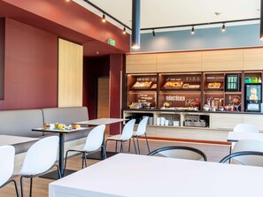 Un espace moderne dédié au petit-déjeuner, avec des sièges et un présentoir pour les aliments.