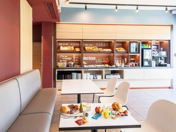 A breakfast area with seating and a buffet counter. - B&B Hotel München City-west (Munich)
