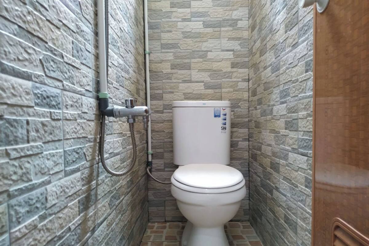 Ein kleines Badezimmer mit Steinoptik, einer Toilette und einer Duschbrause.