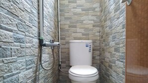 Ein kleines Badezimmer mit Steinoptik, einer Toilette und einer Duschbrause.