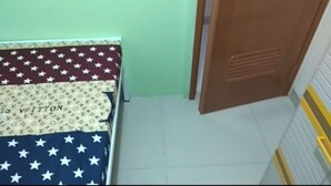 Ein Zimmer mit einem Bett, einer Holztür und einem Fliesenboden.