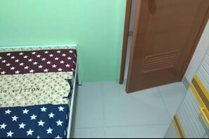 A room with a bed, a wooden door, and a tiled floor. - Eiffel Residence Cideng by Zuzu (Jakarta)