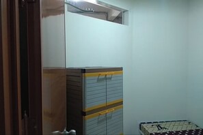 A room with a wardrobe, a bed with patterned bedding, and a plain wall. - Eiffel Residence Cideng by Zuzu (Jakarta)