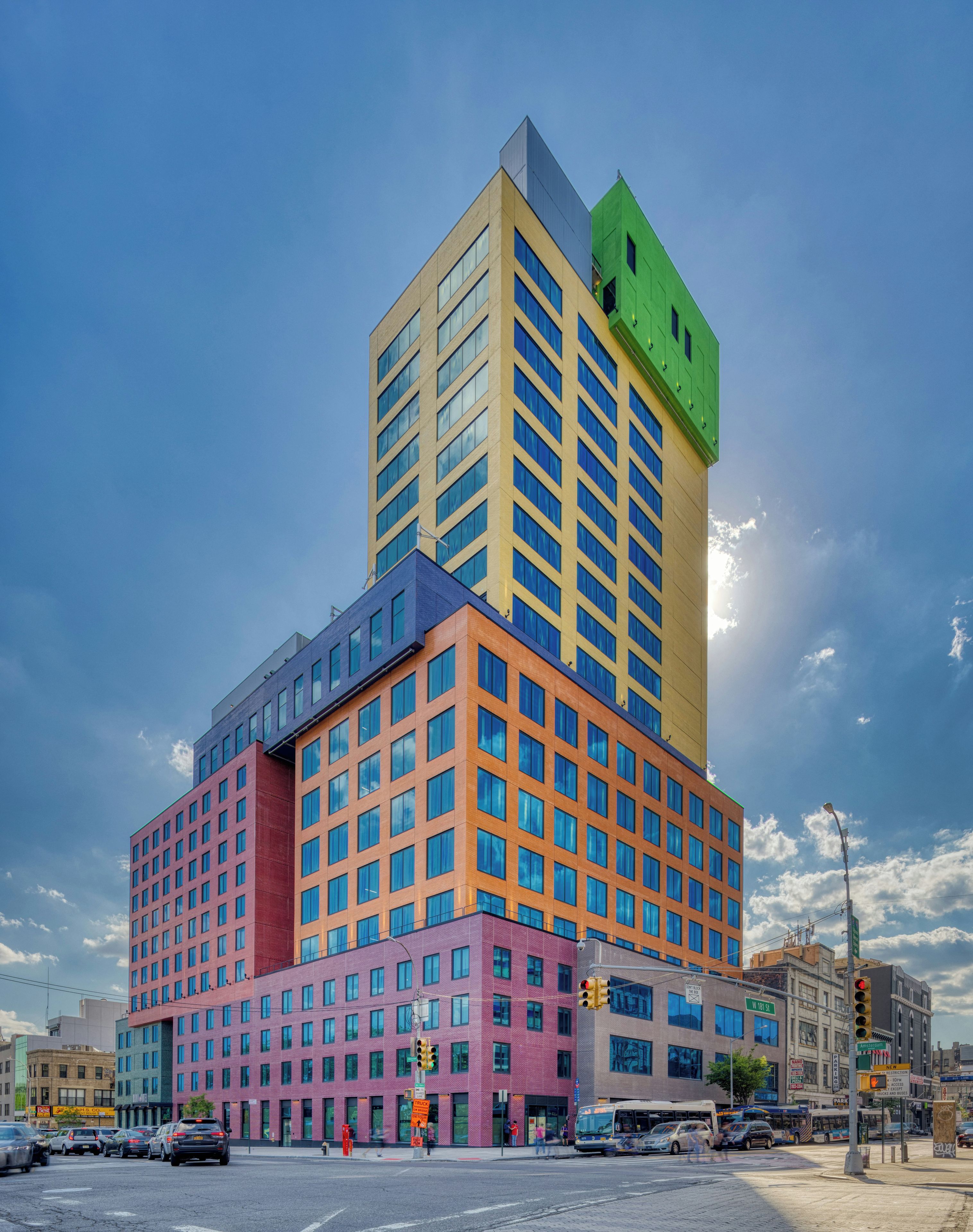A multi-story building with a mix of architectural styles, including a green top, a yellow middle section, and a pink lower section.