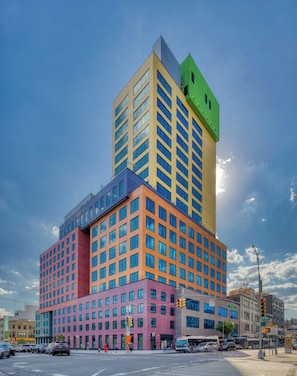A multi-story building with a mix of architectural styles, including a green top, a yellow middle section, and a pink lower section. - Radio Hotel (New York)