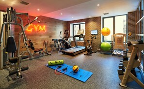A gym with various exercise equipment, a blue mat, and a neon sign. - Radio Hotel (New York)