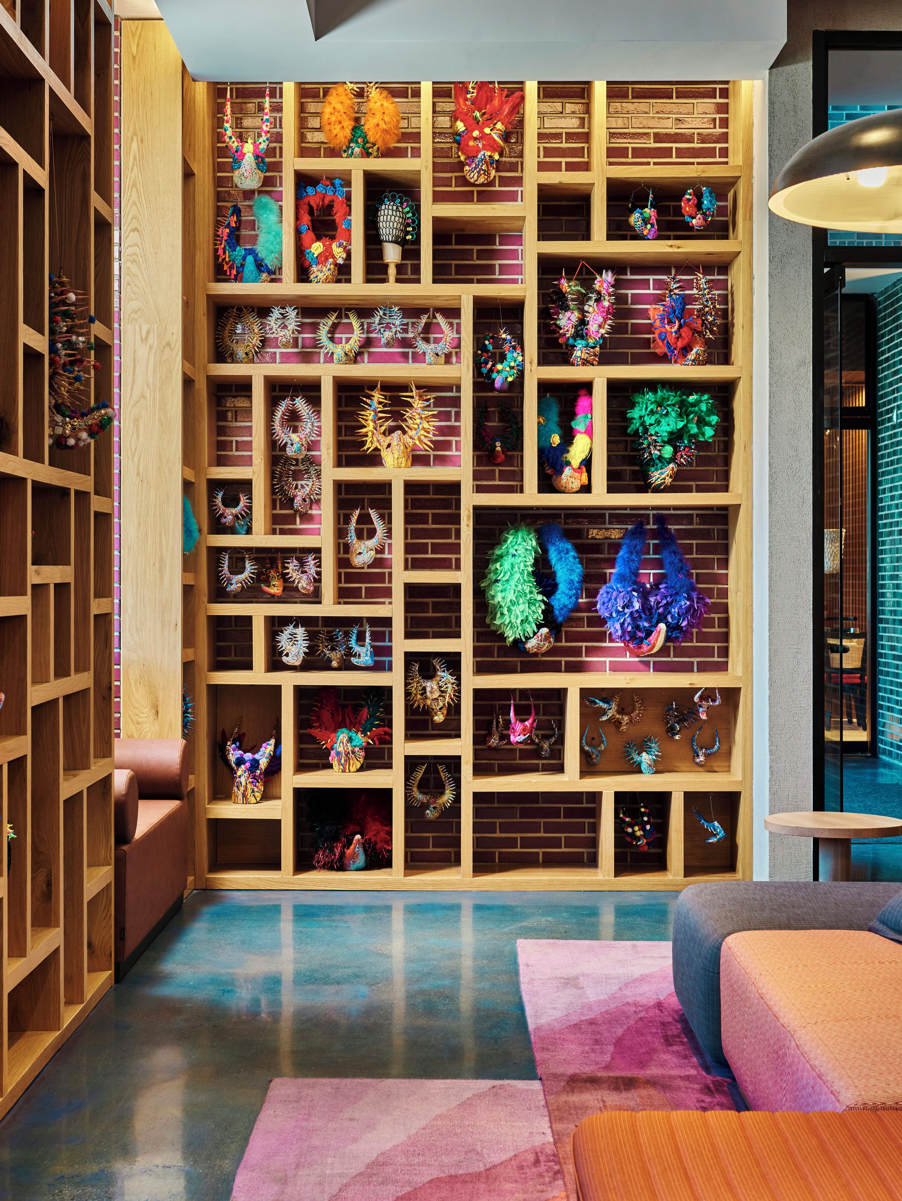 A room with a brick wall and wooden shelving filled with various decorative items.