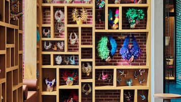A room with a brick wall and wooden shelving filled with various decorative items.