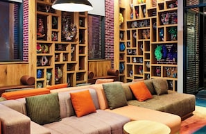 A modern interior with a sectional sofa, wooden shelving with decorative items, and a large window. - Radio Hotel (New York)