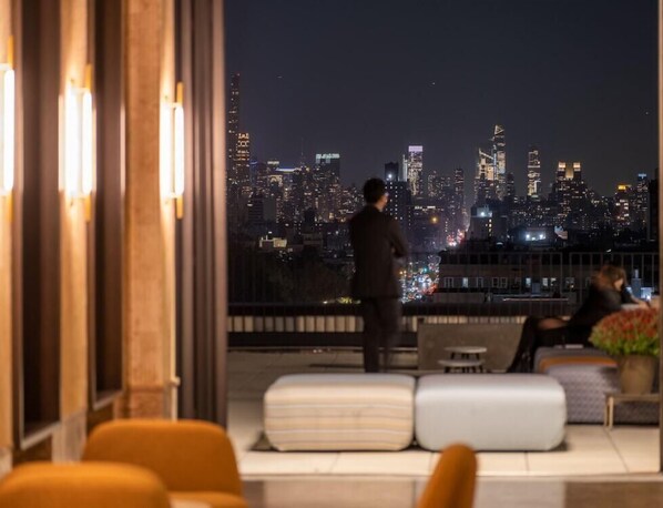 A modern hotel room with a city view, a sofa, and a small table. - Radio Hotel (New York)