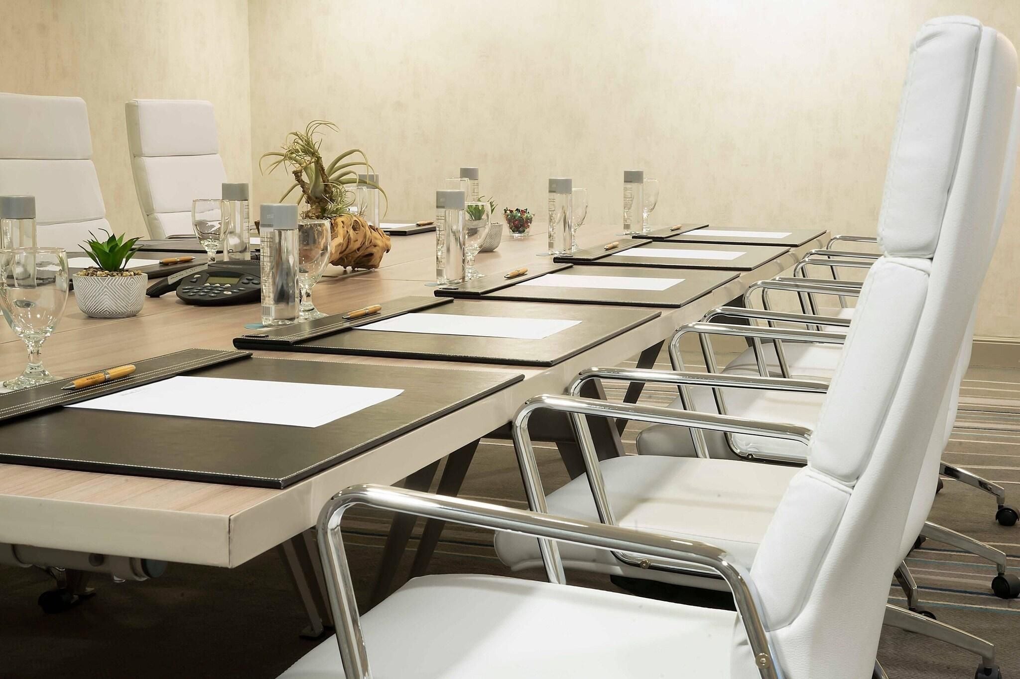 A conference room with a long table, white chairs, and various office supplies.