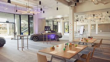 A modern interior with a car, tables, chairs, and a staircase.