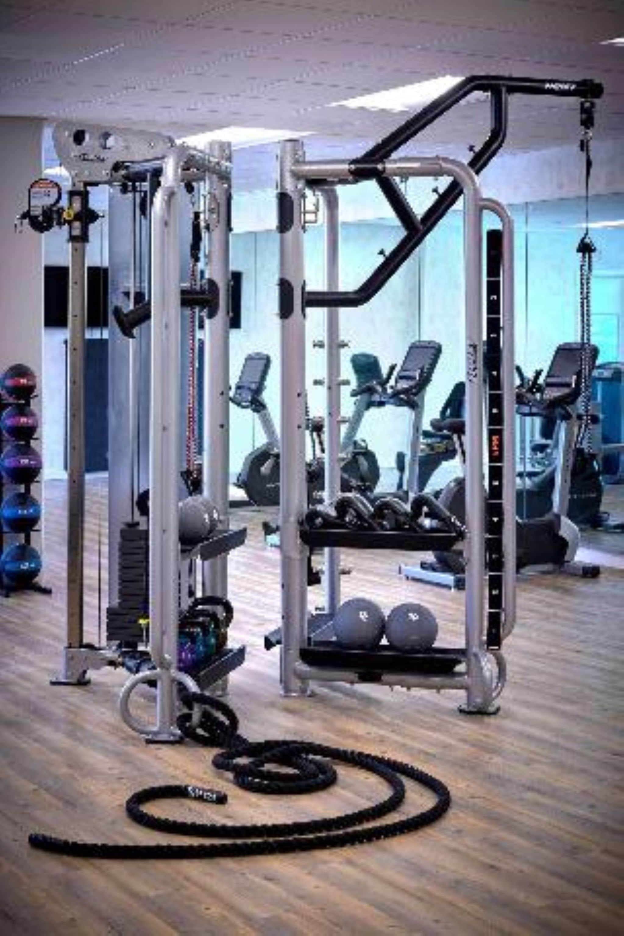 A gym with exercise equipment, weights, and a rope.