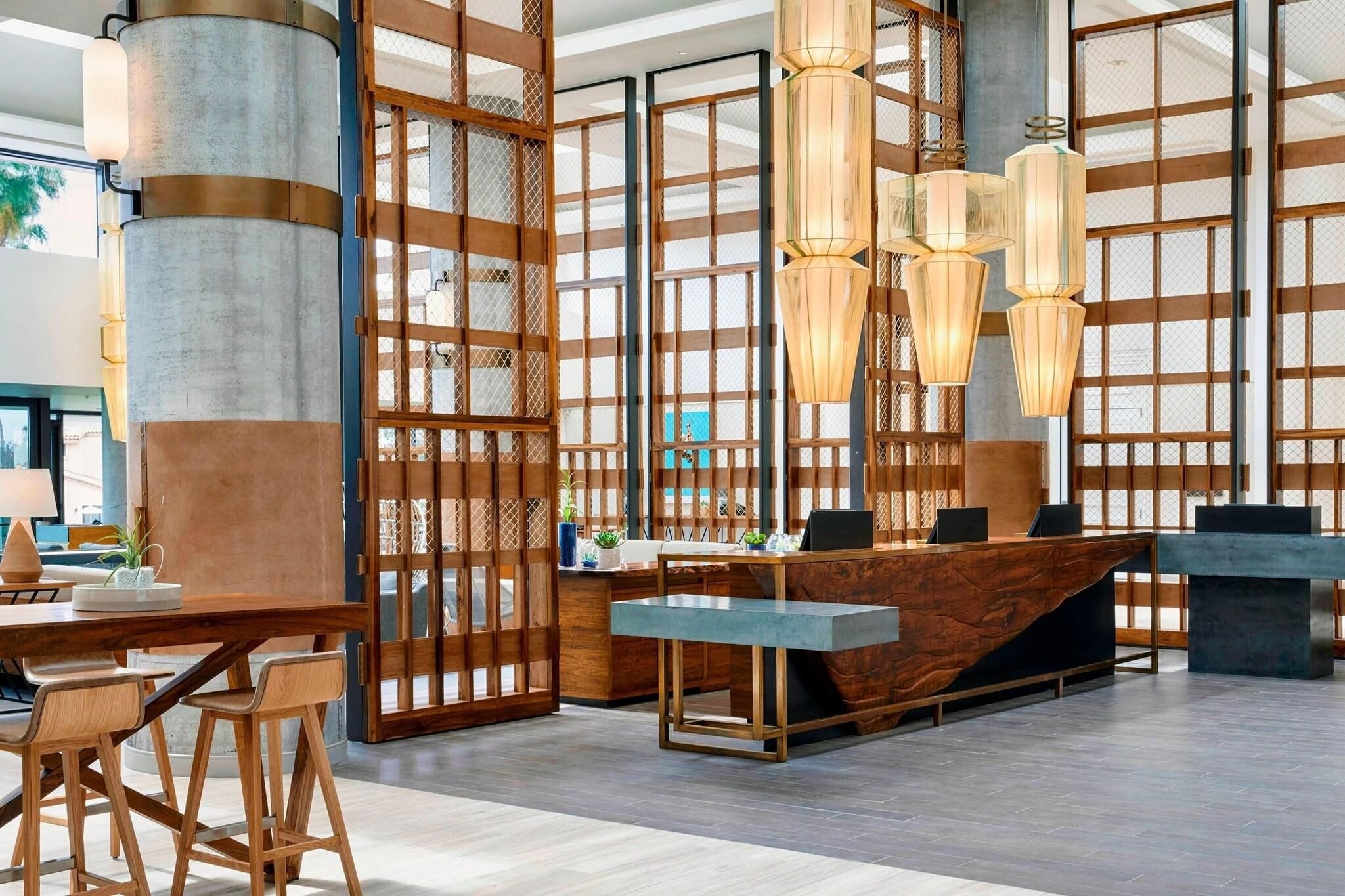 A reception area with a wooden reception desk, modern pendant lights, and a large window with a view.