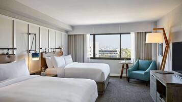 Une chambre d’hôtel avec deux lits, une télévision, un bureau, une chaise et une vue sur la ville.
