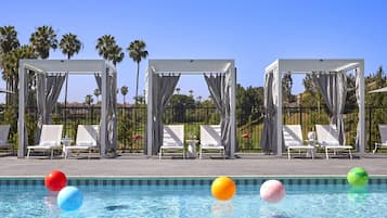 Un espace piscine comprenant des chaises longues, une piscine et une structure en forme de pergola.