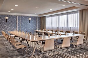 Un salón de conferencias con una larga mesa, sillas y un papel tapiz decorado.