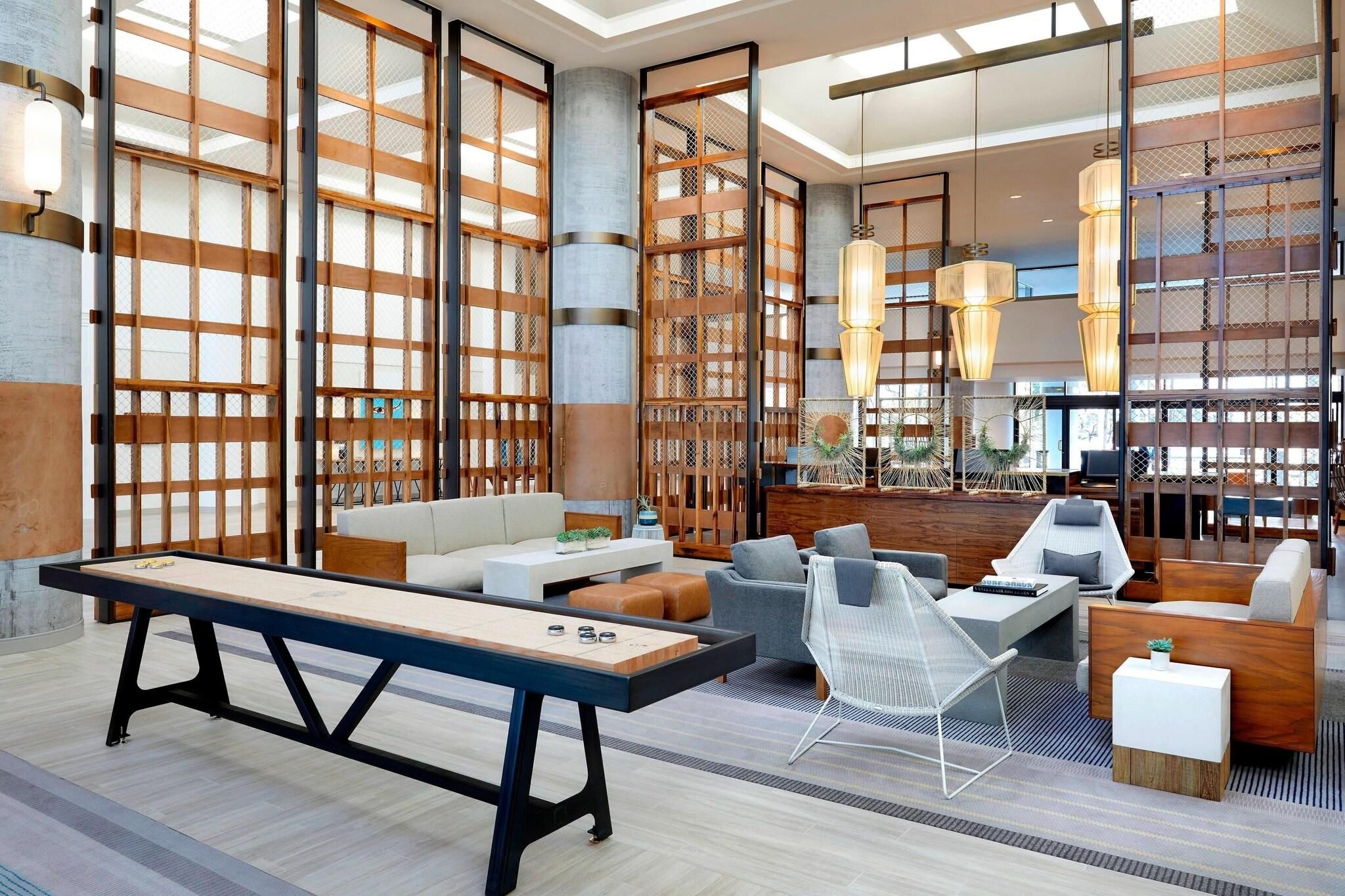 Un intérieur moderne avec une table de billard, un coin salon et de grandes fenêtres.