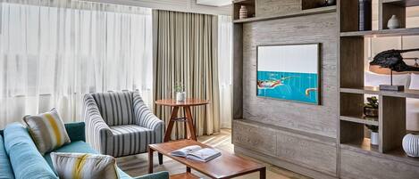 A modern living room with a sofa, armchair, coffee table, and a painting on the wall.