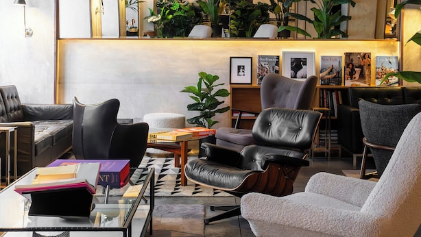 Eine moderne Lounge mit Ledersofas, einem Glastisch und einem Bücherregal mit gerahmten Fotos.