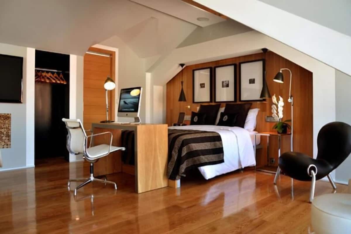 Ein modernes Schlafzimmer mit Bett, Schreibtisch und zwei Stühlen.
