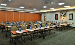 A conference room with rows of tables and chairs, water bottles, name tags, and a projector on the ceiling. - Bon Hotel Empangeni (Empangeni)