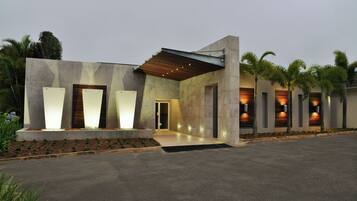 A modern building with a concrete facade, large windows, and a covered entrance.