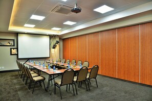 A conference room with a long table, chairs, a projector, and a screen. - Bon Hotel Empangeni (Empangeni)