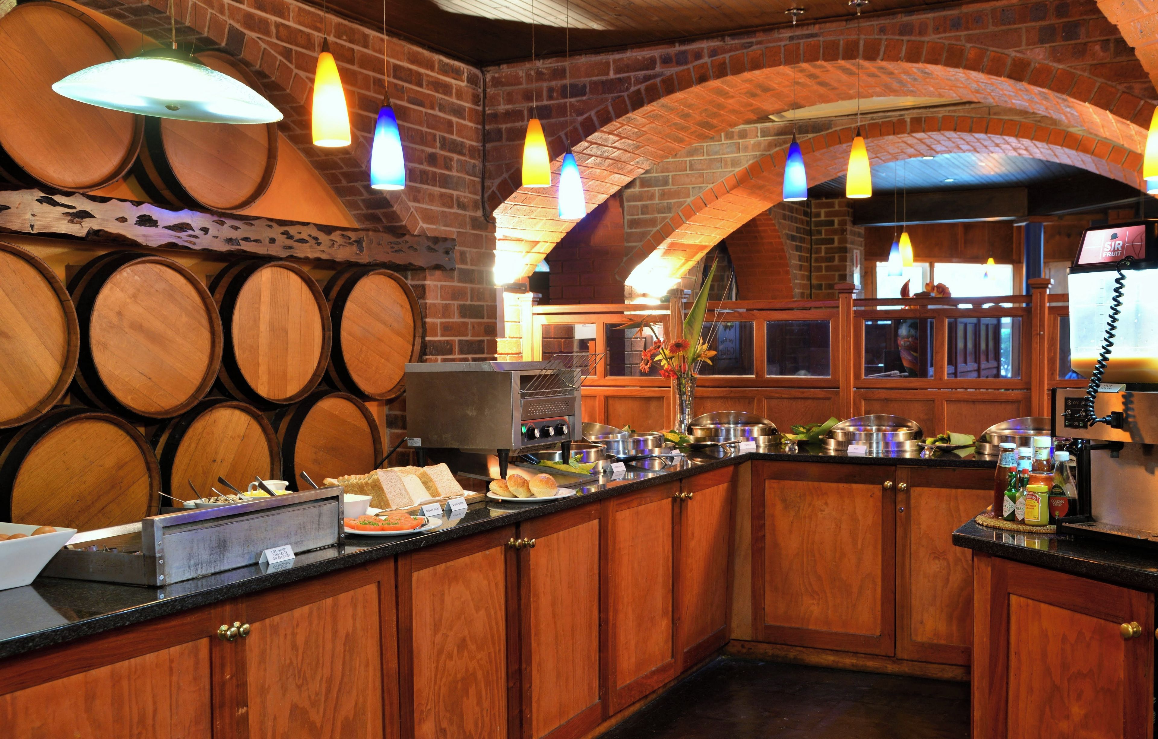 A bar area with wooden barrels, a buffet counter, and a brick wall.