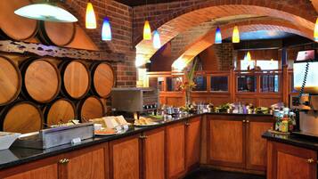 A bar area with wooden barrels, a buffet counter, and a brick wall.