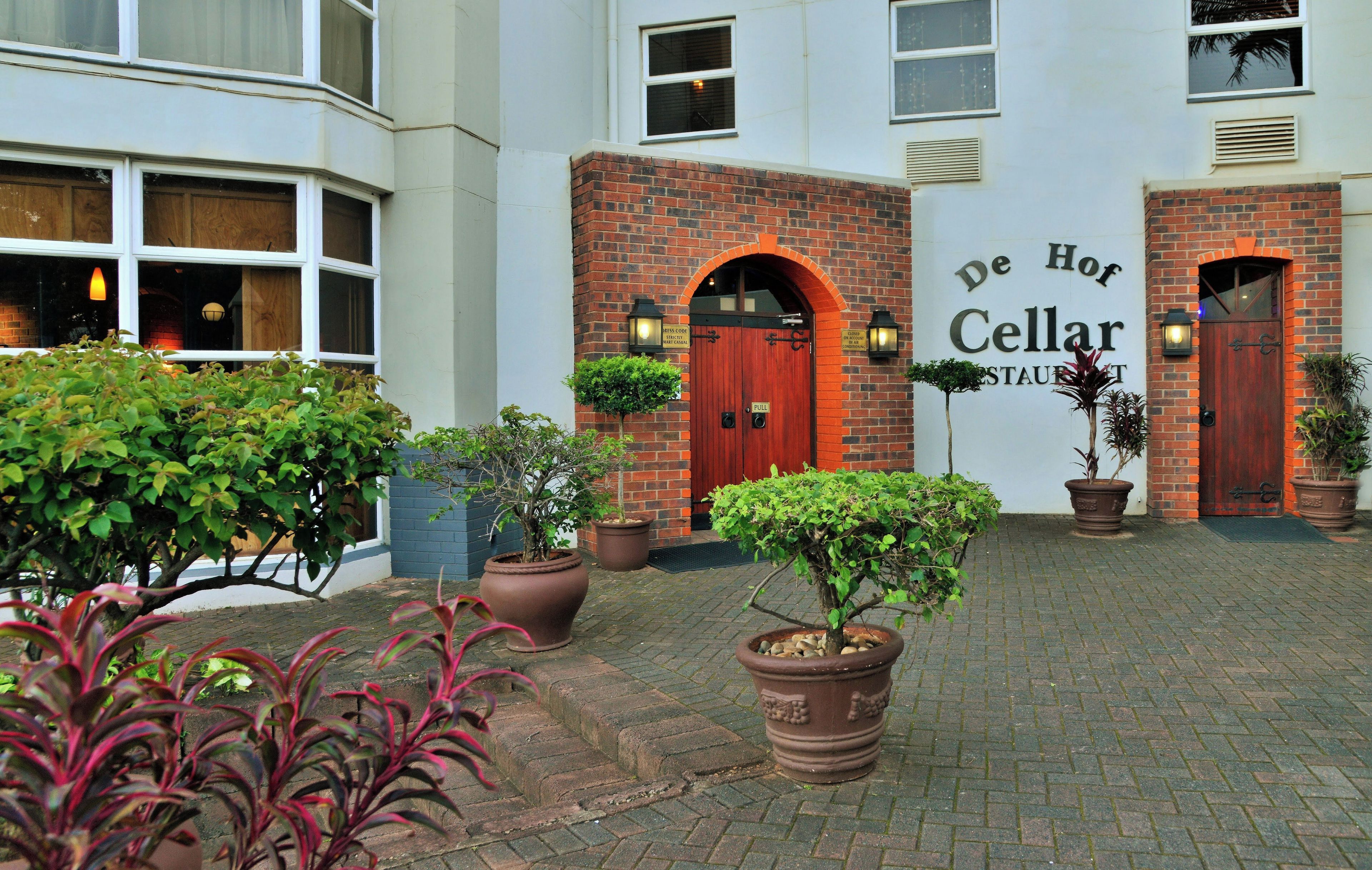 A courtyard with a brick building, two doors, and potted plants.