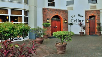 A courtyard with a brick building, two doors, and potted plants.