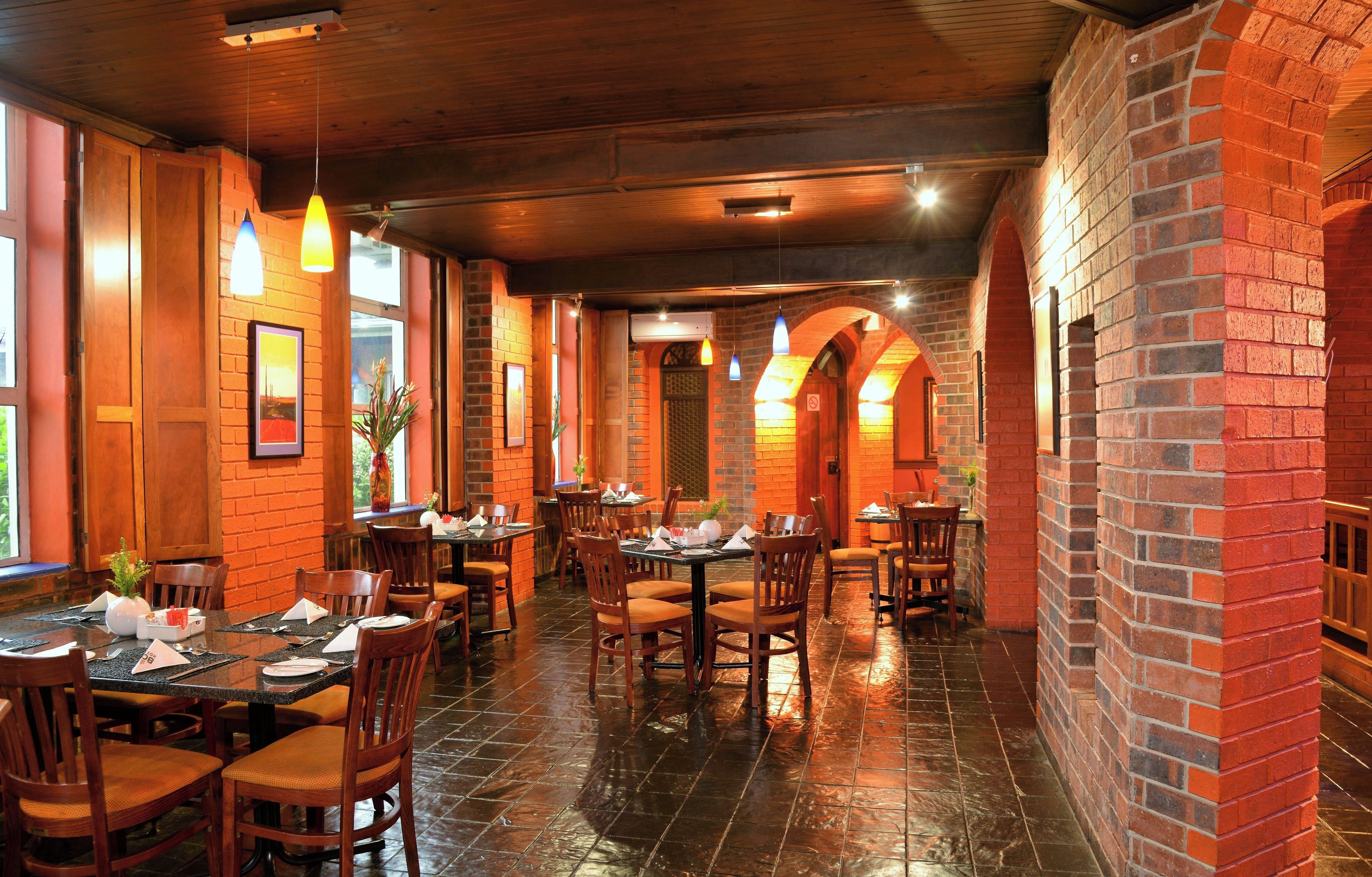 A restaurant interior with brick walls, wooden tables, and hanging pendant lights.