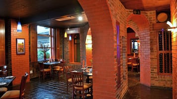 Een restaurantinterieur met bakstenen muren, houten tafels en stoelen.