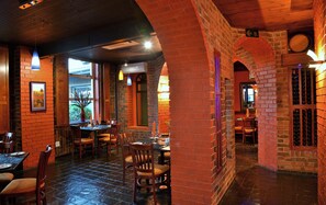 A restaurant interior with brick walls, wooden tables, and chairs. - Bon Hotel Empangeni (Empangeni)