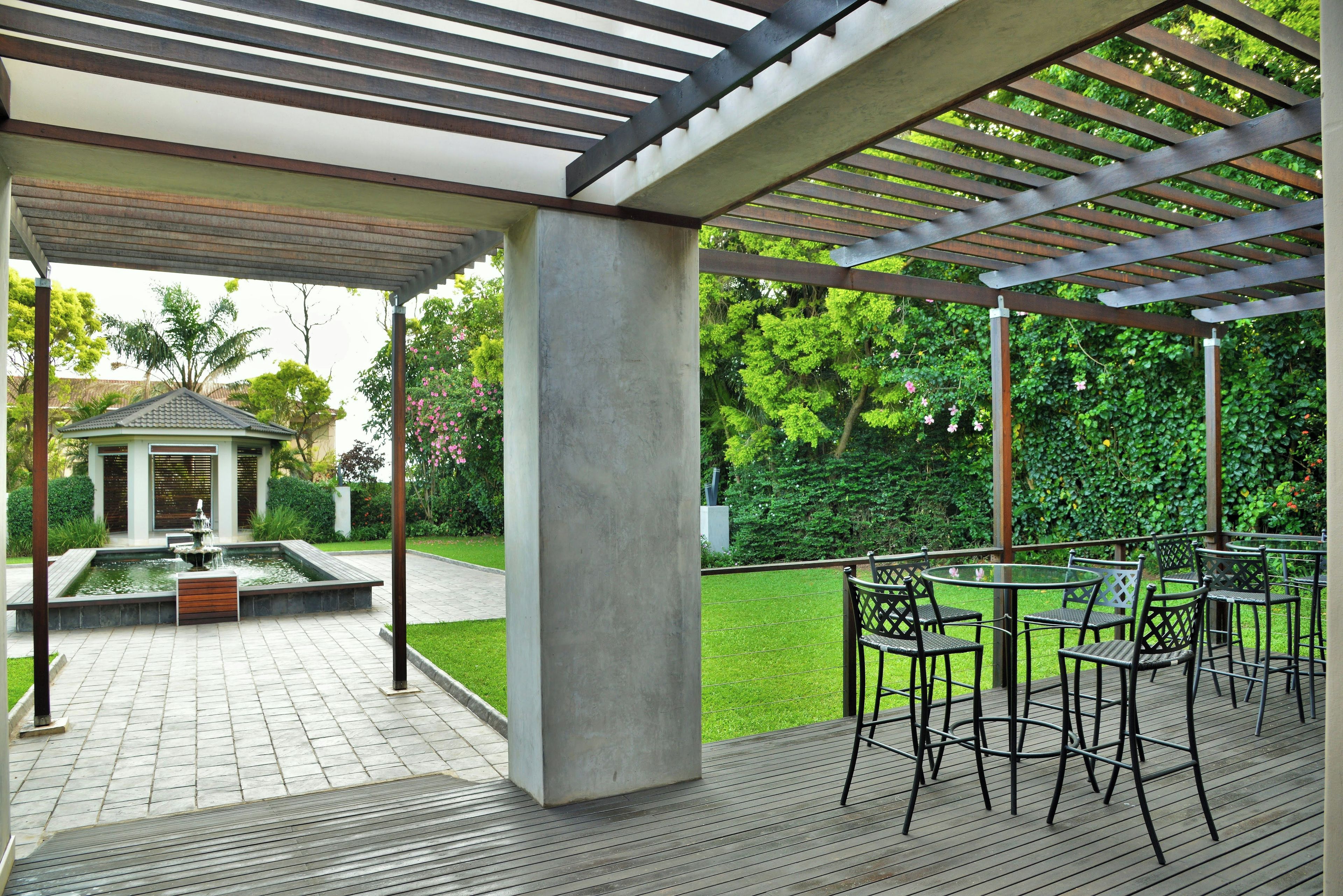 A covered outdoor area with a pergola, seating, and a water feature.