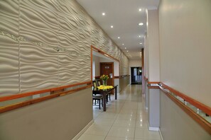 A hotel corridor with a textured wall, a reception desk, and a sign indicating ladies' and push facilities. - Bon Hotel Empangeni (Empangeni)