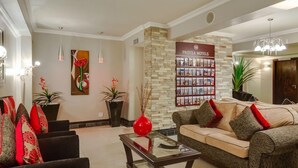A hotel lobby with a reception desk, a sofa, and a coffee table. There is a wall with a sign for 'Protea Hotels' and a display of brochures. - Bon Hotel Empangeni (Empangeni)