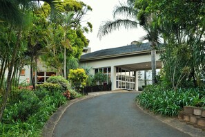 A building with a covered entrance, surrounded by lush greenery and a paved driveway. - Bon Hotel Empangeni (Empangeni)