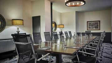 Un salón de conferencias con una larga mesa, sillas y una araña.