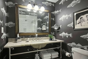 A bathroom with a large mirror, three lights, a sink, a toilet, and fish-themed wall art. - Graduate by Hilton Minneapolis (Minneapolis)
