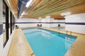 Une piscine aux murs carrelés et au plafond en bois.
